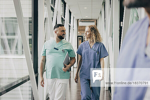 Multiracial male and female hospital staff walking in corridor