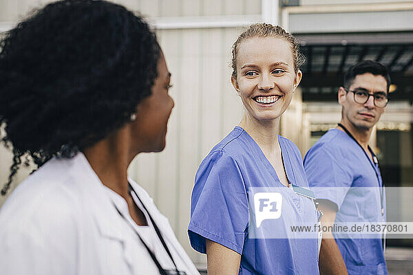 Glückliche Krankenschwester im Gespräch mit einem Arzt außerhalb des Krankenhauses
