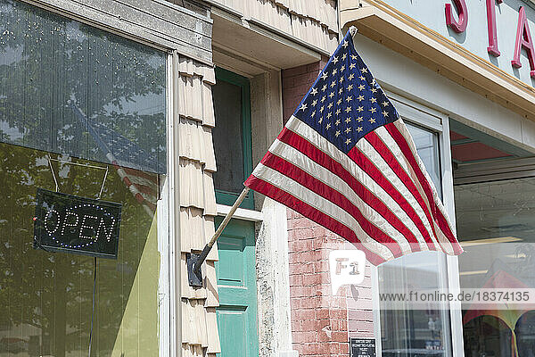 American flag in front of a building  a shop window on main street.