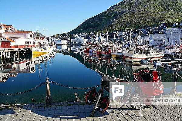 Bicycle in front of harbour with small fishing boats reflected in the calm water  Honningsvag  Finnmark  North Cape  Norway  Europe