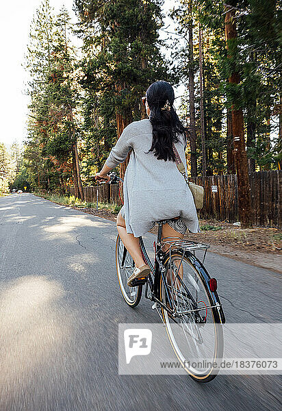 USA  California  Tahoe City  Rear view of woman riding bicycle on road