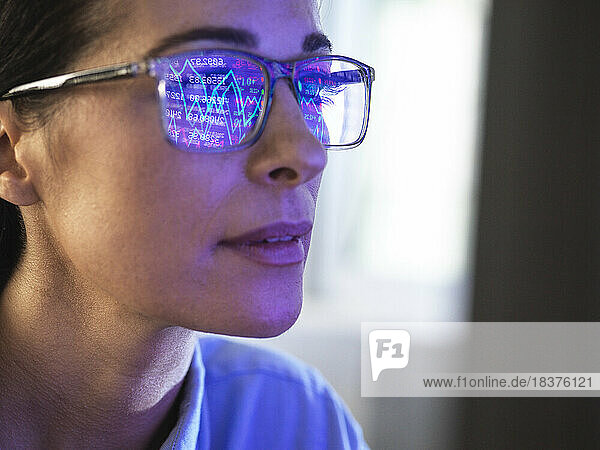 Female expert in glasses looking at screen with financial data