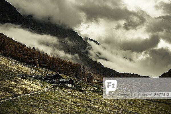 Almhütte in herbstlicher Berglandschaft mit bedrohlichem Wolkenhimmel  Pfossental  Meran  Vinschgau  Südtirol  Italien  Europa