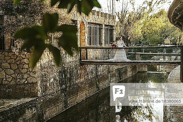 Schöne Braut steht auf hölzernen rustikalen Brücke über einen Fluss bei Sonnenuntergang Zeit