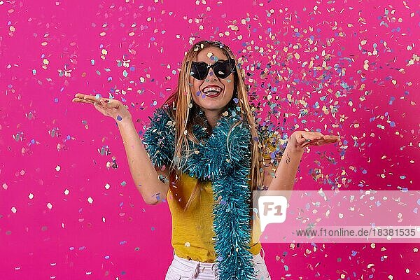 Kaukasisches Mädchen  das in der Disco feiert und lachend Konfetti wirft  vor einem rosa Hintergrund