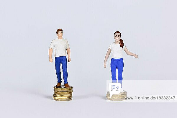 Konzept des geschlechtsspezifischen Lohngefälles mit einem Mann und einer Frau  die auf einer unterschiedlichen Anzahl von Münzen stehen