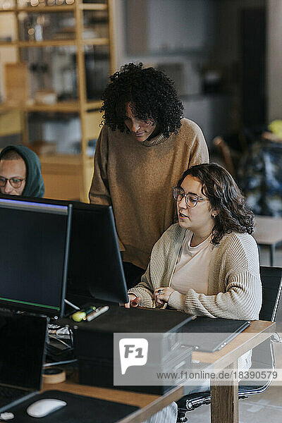 Multirassische Geschäftskollegen diskutieren über Computer am Schreibtisch im Büro