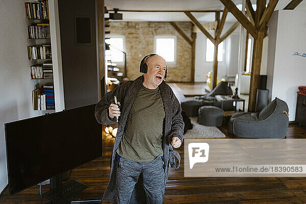 Carefree senior man dancing while listening to music at home