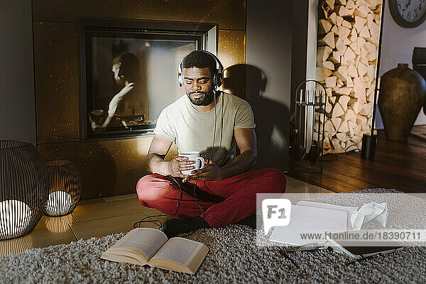 Young man listening to music while reading book at home