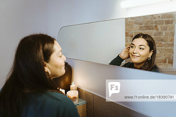 Lächelnde Frau  die sich zu Hause im Spiegel reflektiert