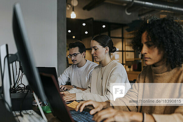 Multirassische Hackerinnen und Hacker arbeiten an einem Laptop an einem kreativen Arbeitsplatz