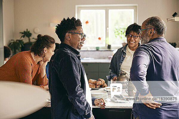 Mehrgenerationen-Familie im Gespräch miteinander  während sie zu Hause in der Küche steht