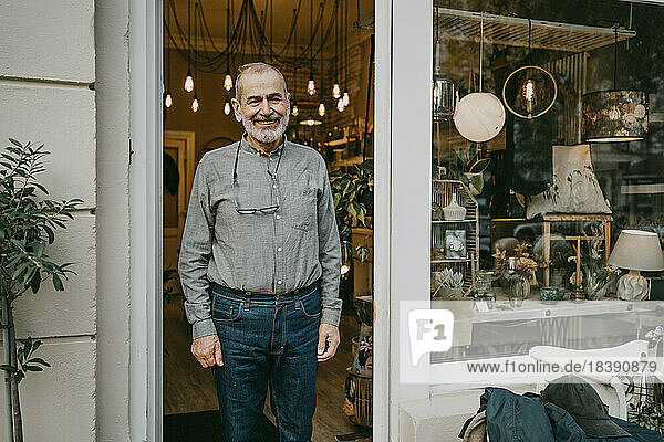 Happy male entrepreneur standing at entrance of home interior shop