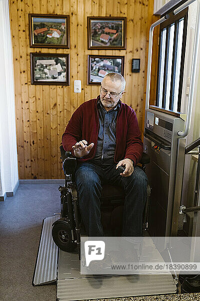 Full length of retired senior man with disability in motorized wheelchair at home