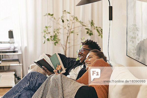 Happy couple enjoying reading books on sofa at home