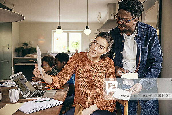 Multiracial couple discussing over financial bill at home