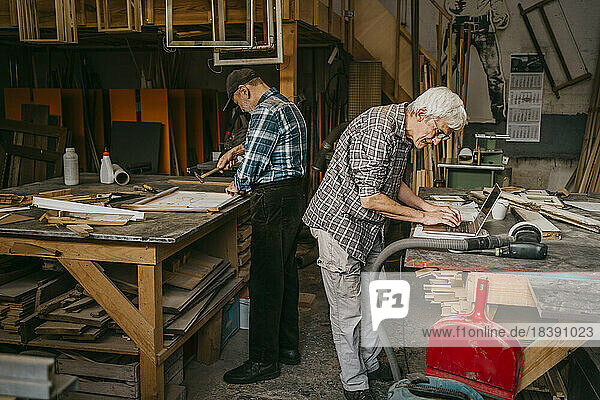 Ältere Handwerker arbeiten in der Schreinerei zusammen