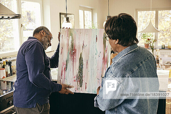 Älteres Paar hilft sich gegenseitig beim Malen zu Hause
