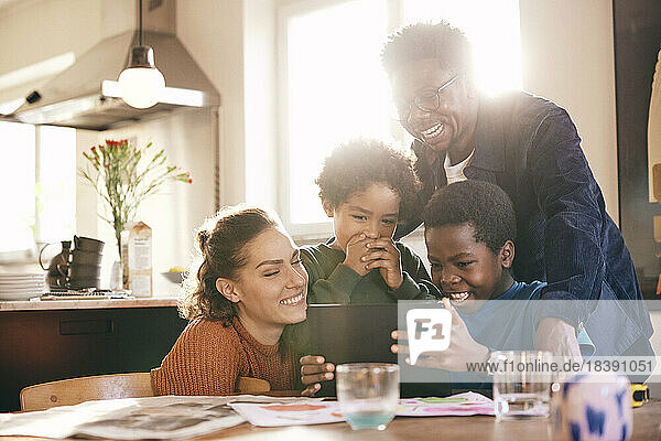Glückliche Familie  die Spaß hat  während sie zu Hause gemeinsam ein digitales Tablet betrachtet