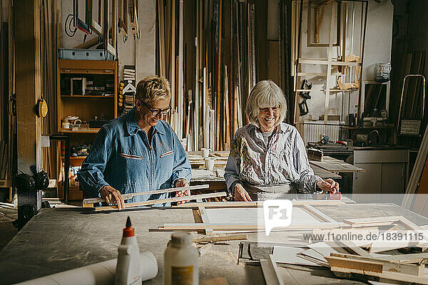 Lächelnde ältere Unternehmerinnen  die sich bei der Arbeit in einer Reparaturwerkstatt unterhalten