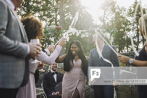 Frisch verheiratete Braut hält die Hand des Bräutigams  während sie inmitten der Gäste bei der Hochzeitszeremonie geht