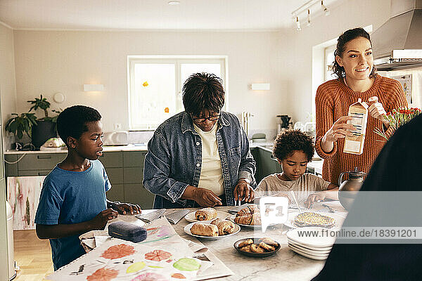 Familie hilft sich gegenseitig bei der Zubereitung des Frühstücks auf der Kücheninsel zu Hause