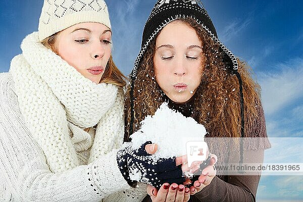 Zwei junge Frauen pusten den Schnee von ihrer Hand