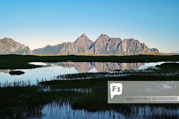Hohe Berge spiegeln sich im ruhigen Wasser eines Sees  Sommer  Stille  Klarheit  Festvagtind  Austvagsoya  Provinz Nordland  Norwegen  Europa