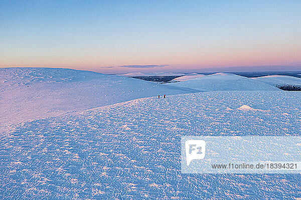 Luftaufnahme von Wanderern beim Skilanglauf bei Sonnenuntergang  Pallas-Yllastunturi-Nationalpark  Muonio  Lappland  Finnland  Europa
