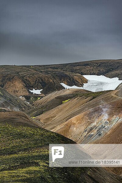 Wanderer auf bunten Rhyolith Bergen mit Schneeresten  Vulkanlandschaft  Erosionslandschaft  Landmannalaugar  Fjallabak Naturreservat  isländisches Hochland  Suðurland  Island  Europa