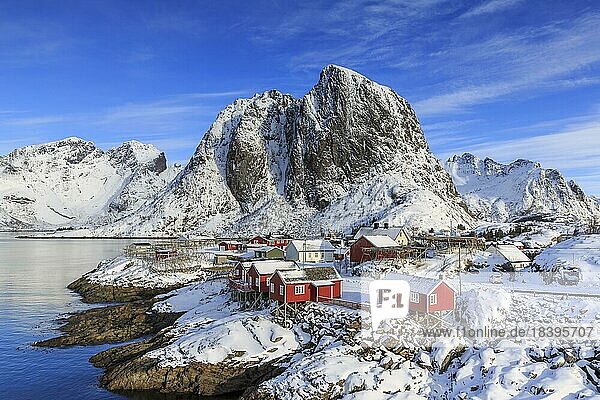 Rote Rorbuer im Winter  Fischerhütten  hinten schneebedeckter Berg Festhæltinden  Hamnøy  Lofoten  Nordland  Norwegen  Europa