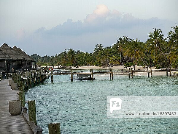 Ferieninsel auf den Malediven  Mit Schwimmbad  Hütten und Sonnenliegen  bei Sonnenuntergang  Malediven  Indischer Ozean  Asien