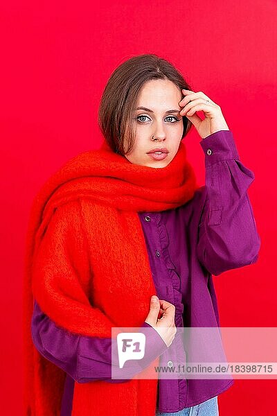 Close up Porträt einer jungen kaukasischen Frau in lila Shirt vor rotem Hintergrund  trägt einen Schal Blick in die Kamera