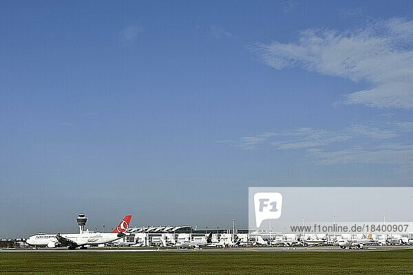 Aircraft taking off Turkish Airlines Airbus A350-900  Pegasus and Lufthansa on runway south with tower  Munich Airport  Upper Bavaria  Bavaria  Germany  Europe