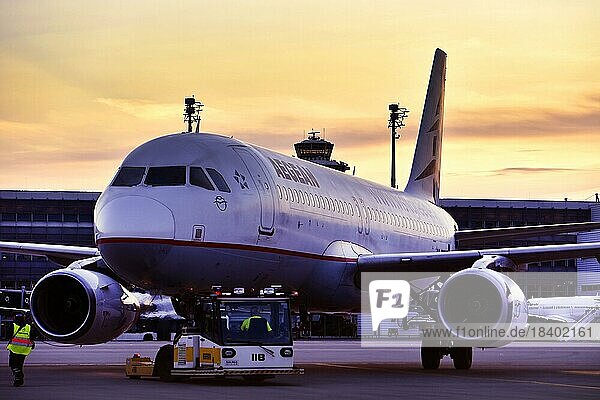 Agean Airlines aircraft towing in front of Terminal 2 in the sunset  Munich Airport  Upper Bavaria  Bavaria  Germany  Europe