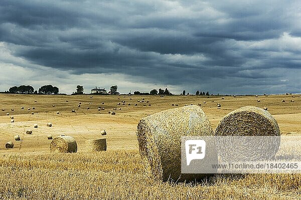Storm clouds building over recently harvested straw bales. Concept for dangers and threats to the farming industry
