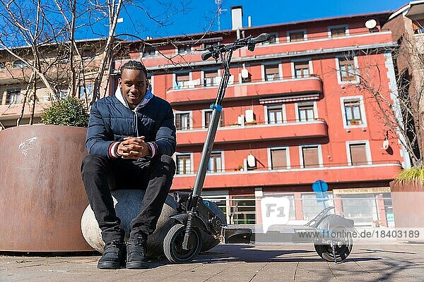 Porträt eines schwarzen ethnischen Mannes  der auf einem elektrischen Skateboard in der Stadt fährt  neue Mobilität