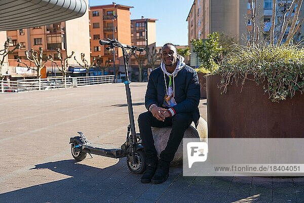 Porträt eines schwarzen ethnischen Mannes  der auf einem elektrischen Skateboard fährt  neue Mobilität