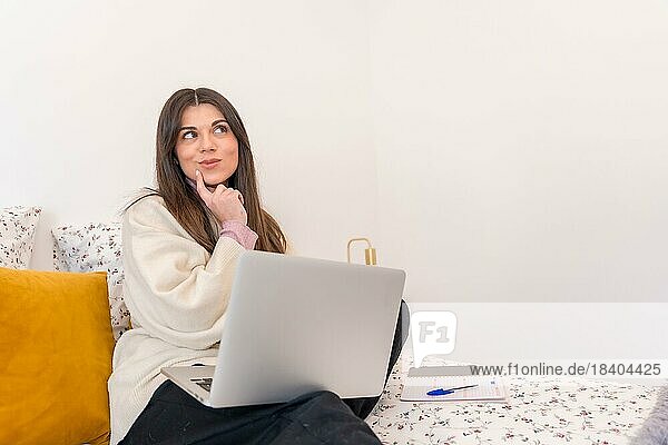 Porträt einer Frau mit Laptop im Bett  nachdenklich  Telearbeit  Kopierraum