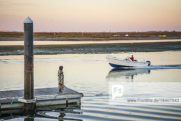 Eine Frau auf einem Pier  die zu einem Mann auf dem Boot schaut  am frühen Morgen in Faro  Algarve