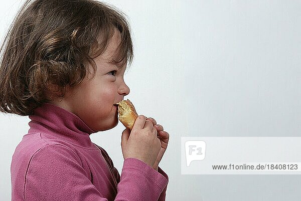 Ein junges Mädchen isst ein Brötchen