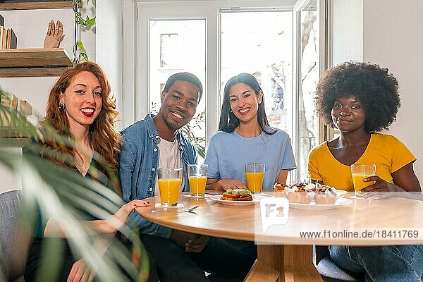Porträt von multiethnischen Freunden beim Frühstück mit Orangensaft und Muffins zu Hause