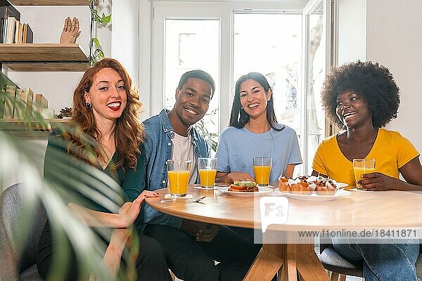Portrait of multi-ethnic friends having a breakfast with orange juice and muffins at home