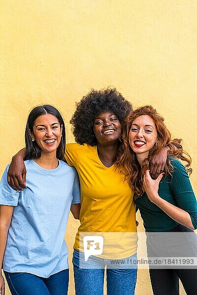 Porträt von schönen multiethnischen Freundinnen  die auf einer gelben Wand lächelnd Spaß haben  Copy Paste