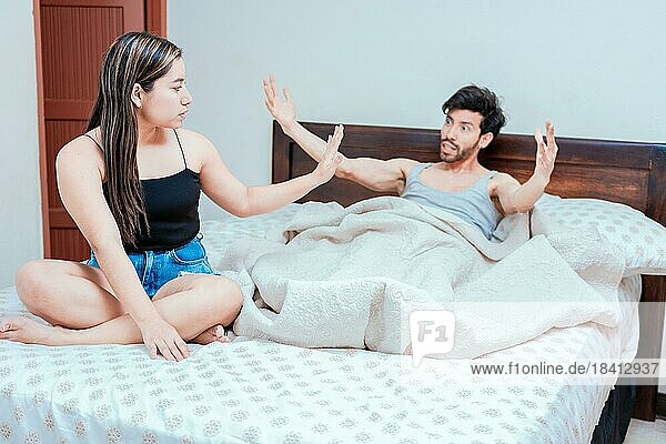 Upset woman with husband in bedroom bed  Husband fighting with his wife in bed. Young couple arguing in bed room. Concept of couple problems in bed