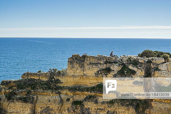Eine Frau auf der Spitze der Klippen am Strand von Marinha in der Algarve  Südportugal