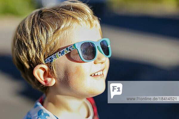 Kleinkind mit Sonnenbrille  genießt herbstliche Sonnenstrahlen. Bonn  Deutschland  Europa