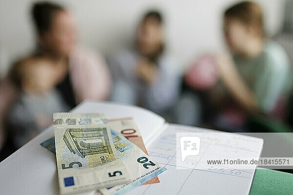 Haushaltsbuch mit fünfunddreissig Euro. Im Hintergrund eine Mutter mit drei Kindern.  Bonn  Deutschland  Europa