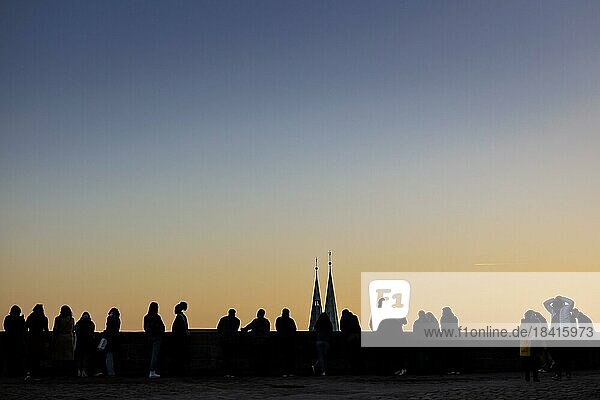 Personen stehen bei Sonnenuntergang auf einer Aussichtsplattform der Kaiserburg Nürnberg. Die Türme der Sebalduskirche sind dahinter zu sehen. Nürnberg  13.02.2023.  Nürnberg  Deutschland  Europa