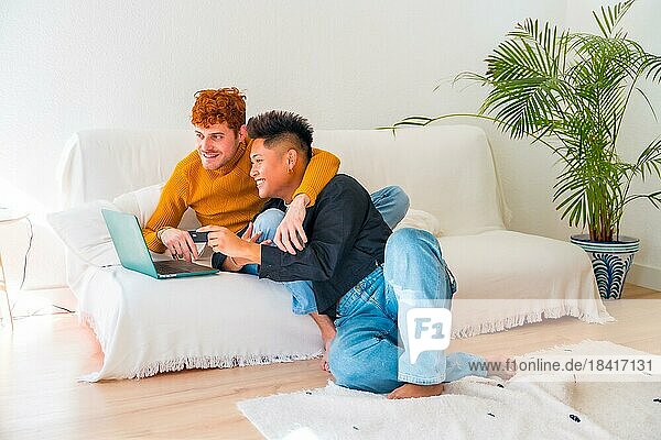 Beautiful gay couple being romantic on the sofa hugging  lgbt concept  doing online shopping